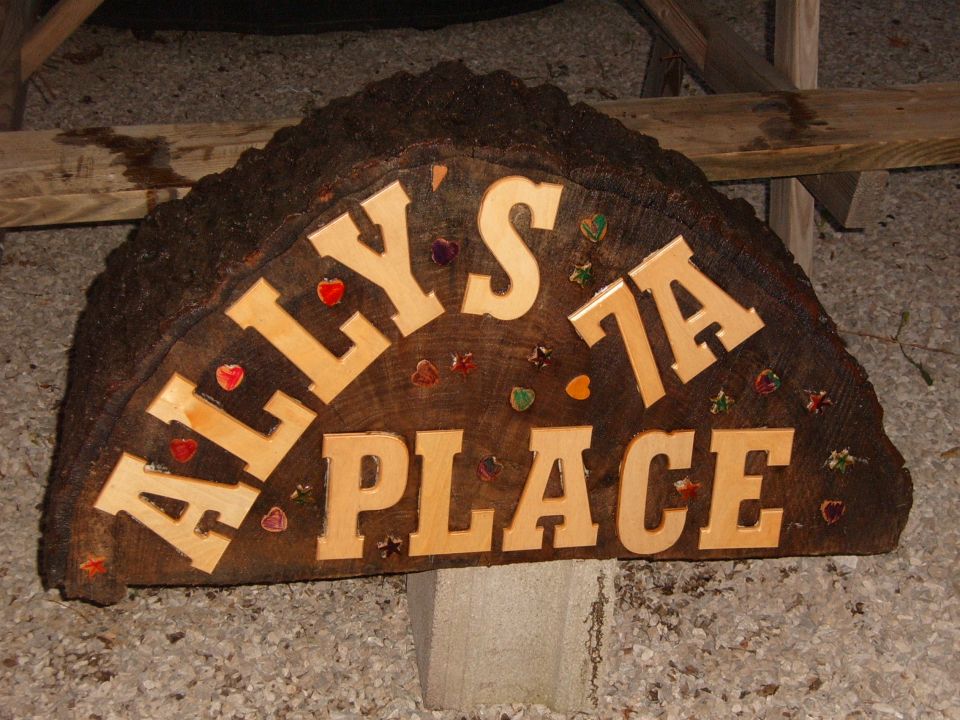 Wooden sign that says Ally's 7A Place, decorated with colorful heart and apple shapes