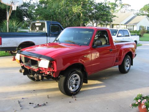 1974 Ford F-100 - A red Ford Ranger pickup truck is parked in a driveway with its front end partially disassembled. Another truck is visible in the backgroun…