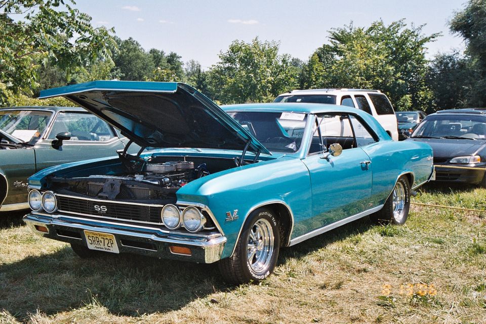 1966 Chevrolet Chevelle SS coupe with hood open, parked on grass next to other cars