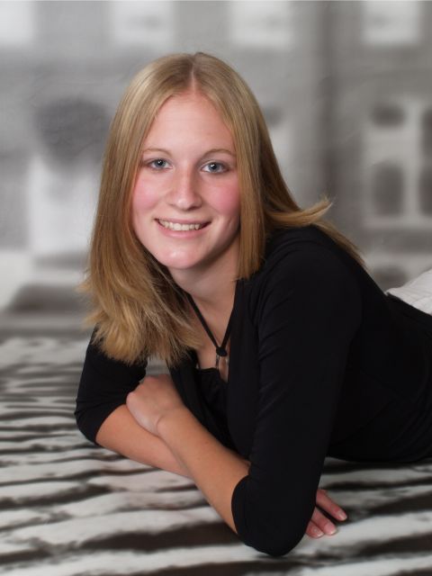 1996 Ford Bronco - A young woman with blonde hair smiles while lying on a striped rug in front of a blurred background.