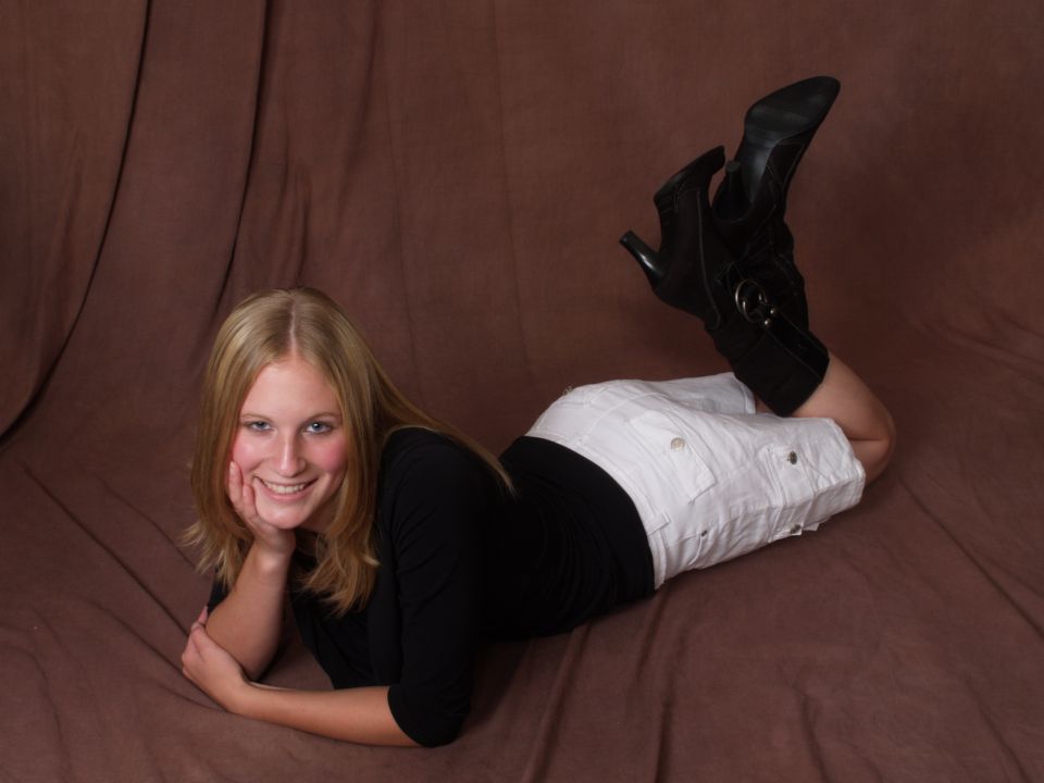 Woman in black top and white shorts with black boots lying down