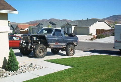 1986 Ford Bronco - Modified blue Ford Bronco with large tires and a lifted suspension sits in a driveway under a clear sky.