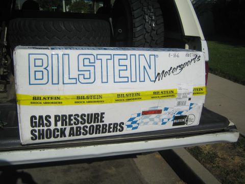 1990 Ford Bronco - Bilstein Motorsports gas pressure shock absorbers box sits on a vehicle's rear bumper with a tire behind.