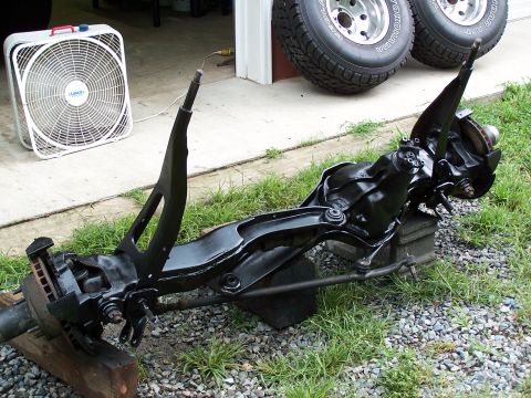 1983 Ford Bronco - Suspension components are laid out on the grass, possibly for a lift installation, with a fan and tires nearby.