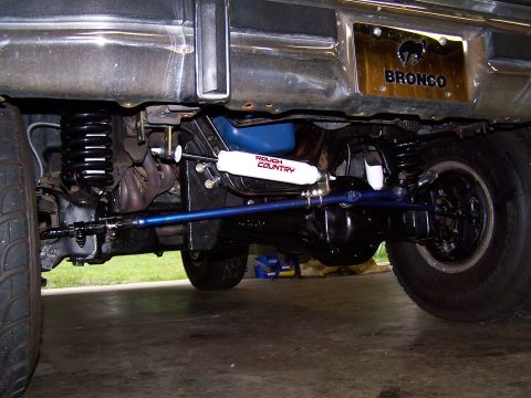 1983 Ford Bronco - The rear axle and suspension components of a Ford Bronco are visible, along with a steering stabilizer.