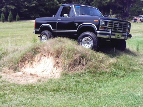 1983 Ford Bronco - This lifted 1983 Ford Bronco is shown in a three-quarter front view, parked on a grassy hill.