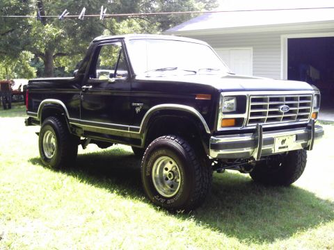 1983 Ford Bronco - This black 1983 Ford Bronco is parked on a grassy lawn near a residential garage.