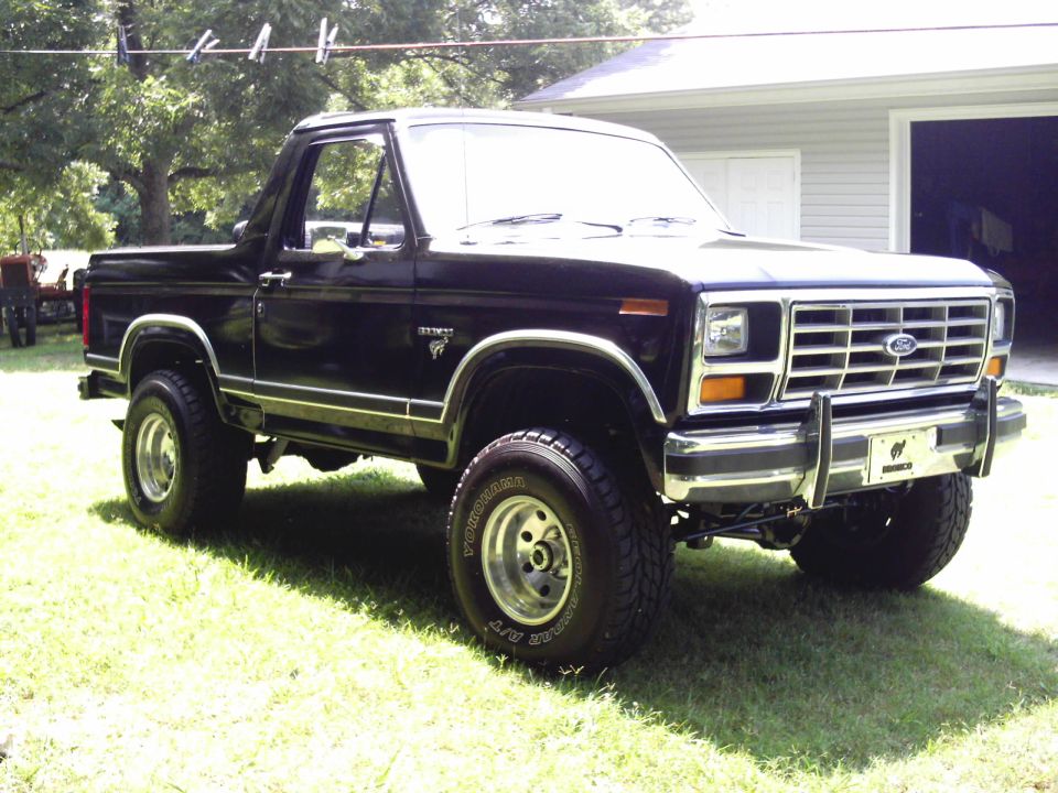 Black Ford Bronco on lifted suspension parked on grass near a garage
