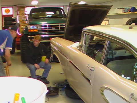 1996 Ford Bronco - Two vehicles are in a garage, both with their hoods open, as two people appear to be working on them.