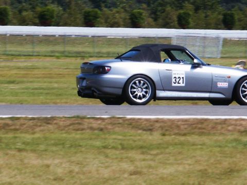2001 Mercury Grand Marquis - A silver convertible sports car with racing decals is seen on a race track.
