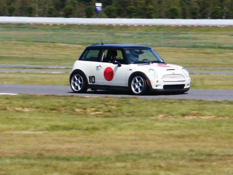 2001 Mercury Grand Marquis - A white Mini Cooper with racing decals, including a red circle and the number 10, navigates a turn on a race track.
