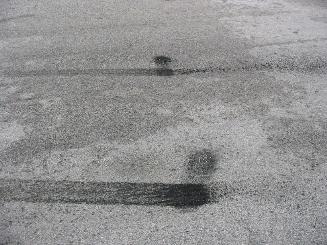 Tire marks and dark fluid stains on asphalt