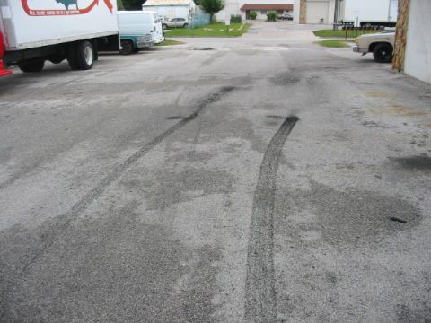 1985 Ford Crown Victoria LTD - Tire marks indicate recent burnout activity in a parking lot with multiple vehicles present.