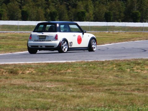 2001 Mercury Grand Marquis - A white Mini Cooper with a black roof and racing decals is seen from the rear on a track.