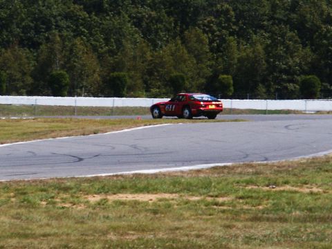 2001 Mercury Grand Marquis - A red sports car is seen on a race track, with the number 611 visible on its side.