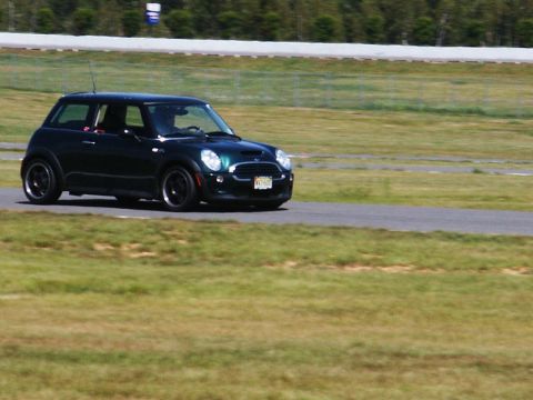 2001 Mercury Grand Marquis - A dark green Mini Cooper is seen on a race track during a sunny day.
