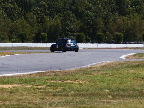2001 Mercury Grand Marquis - A dark green hatchback car is seen from the rear on a race track, with a white stripe visible on its side door.