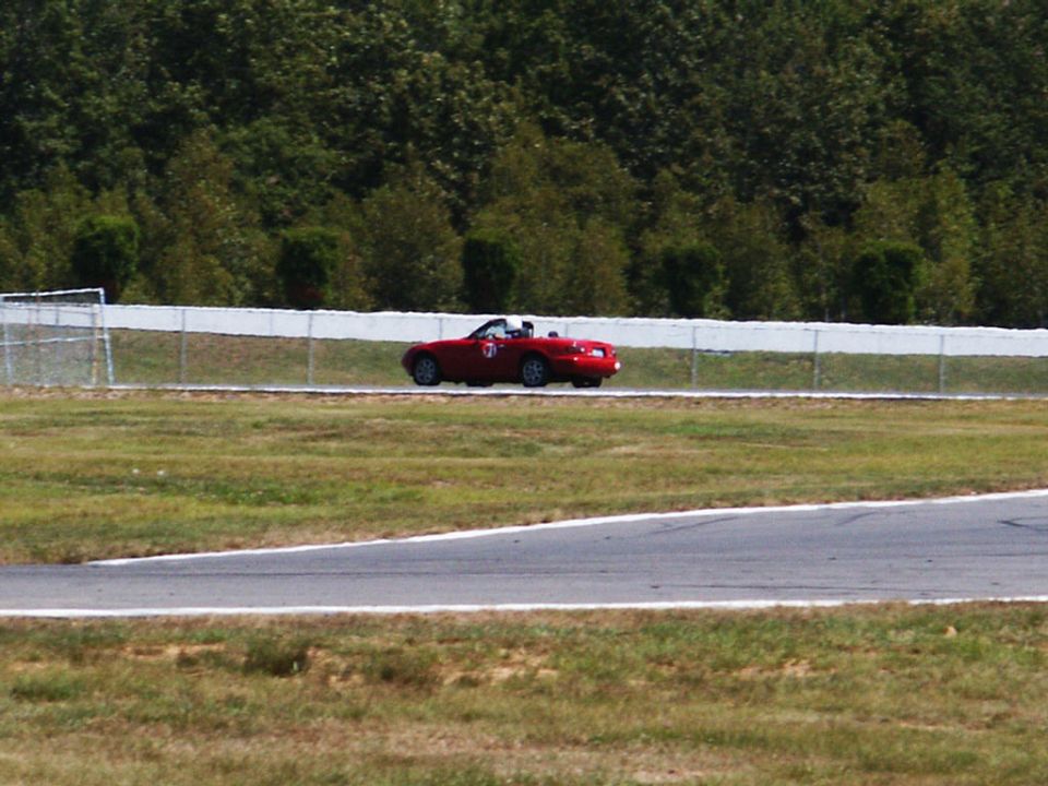 Red convertible sports car with a number 7 on the side driving on a race track
