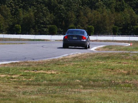 2001 Mercury Grand Marquis - A dark sedan navigates a turn on a race track.
