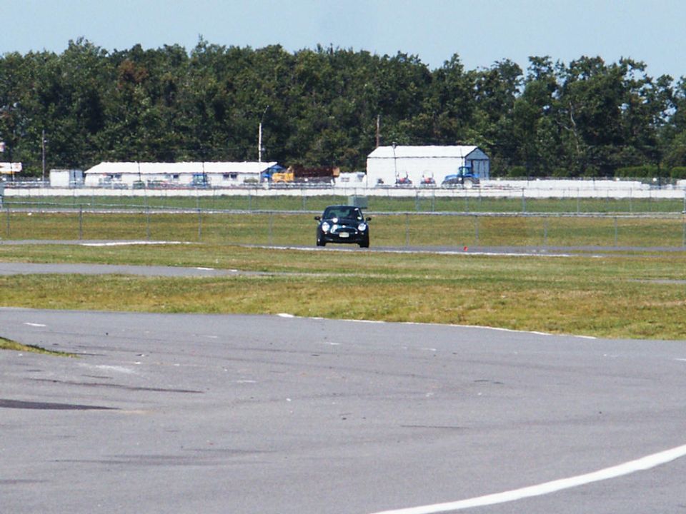 Black car on a racetrack, front view, distant