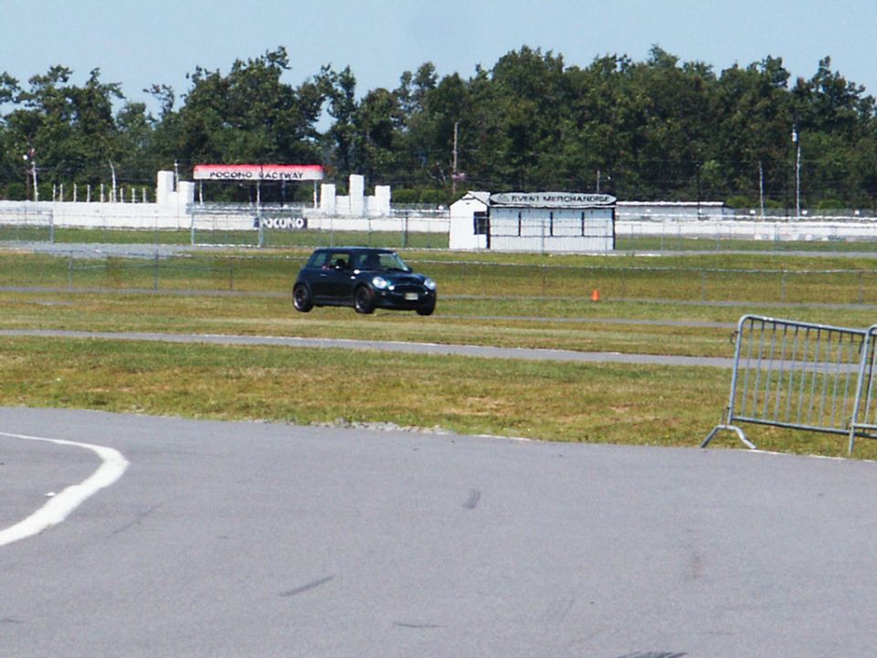 Black Mini Cooper on racetrack with Pocono Raceway signage