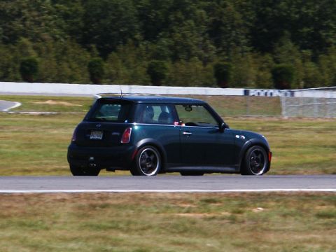 2001 Mercury Grand Marquis - A dark green Mini Cooper is seen on a race track during a sunny day.