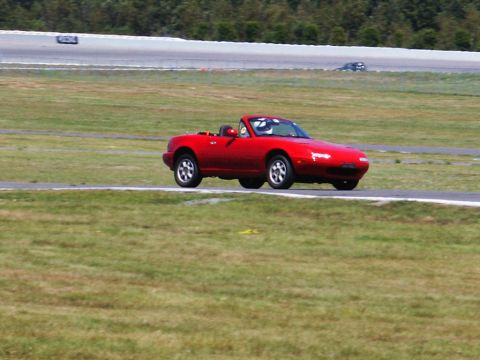 2001 Mercury Grand Marquis - A red convertible is on the track during a race event.