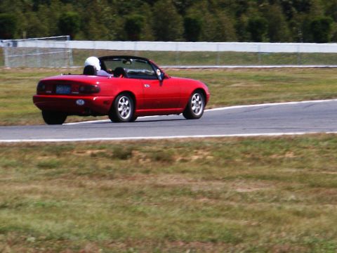 2001 Mercury Grand Marquis - A red convertible sports car is seen from the rear on a race track.