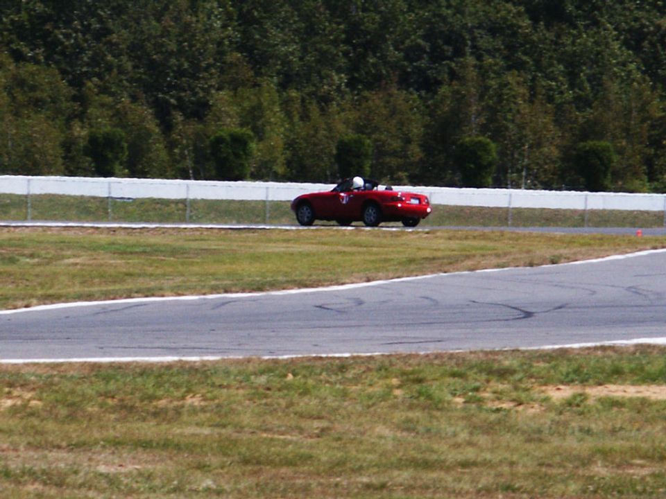 Red convertible sports car on a race track, side view