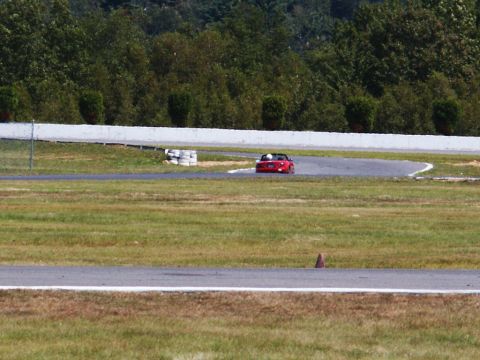 2001 Mercury Grand Marquis - A red convertible navigates a turn on a race track with trees in the background.