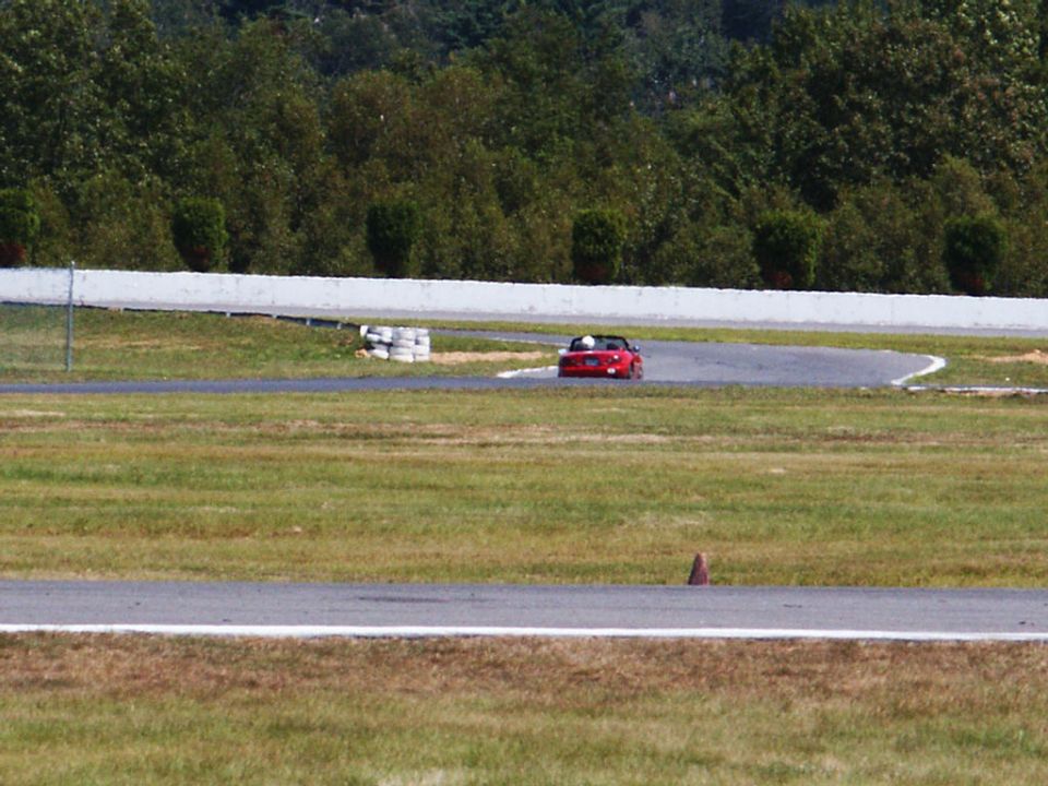 Red convertible sports car on a race track, seen from behind