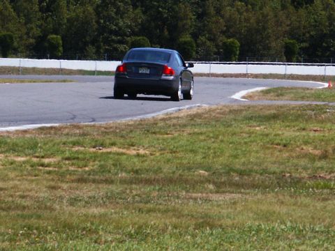 2001 Mercury Grand Marquis - A dark sedan navigates a turn on a race track, with a watermark for SUPERMOTORS visible at the bottom right.
