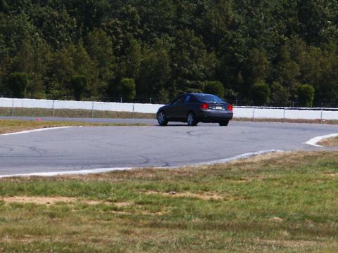 2001 Mercury Grand Marquis - A dark sedan navigates a turn on a paved race track.