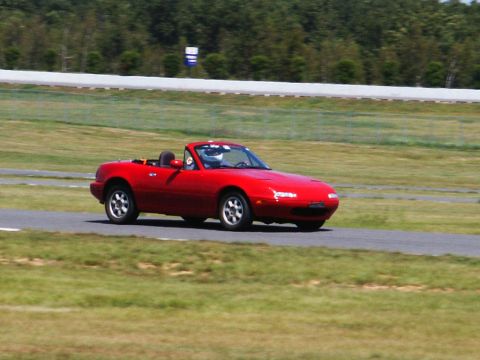 2001 Mercury Grand Marquis - A red convertible sports car is driven on a race track with a driver wearing a helmet.