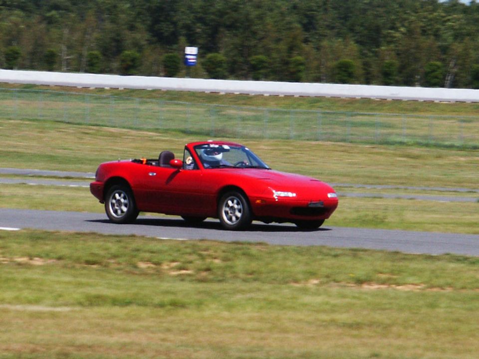 Red convertible sports car with a driver wearing a helmet on a race track