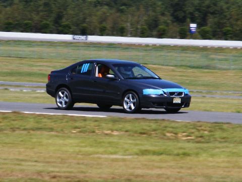 2001 Mercury Grand Marquis - A dark sedan is captured in motion on a race track, with blue tape applied to its front end.