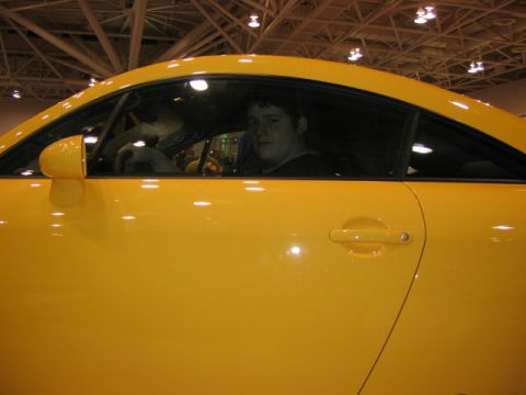 1994 Mazda 626 - A person sits inside a yellow coupe, viewed from the side.