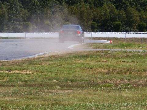 2001 Mercury Grand Marquis - A dark sedan drifts on a race track, creating a cloud of dust as it navigates a turn.