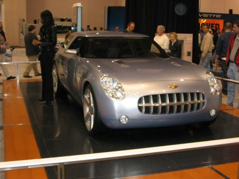 1994 Mazda 626 - A silver concept car is displayed indoors, a distinctive chrome grille and round headlights.