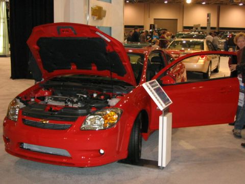 1994 Mazda 626 - A red Chevrolet Cobalt is displayed with its hood and driver door open at an auto show.