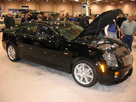 1994 Mazda 626 - A black sedan is displayed with its hood open at an auto show, revealing the engine compartment.