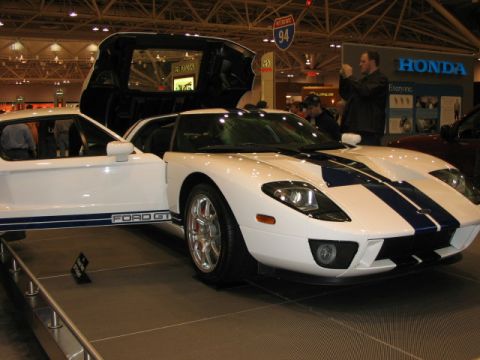 1994 Mazda 626 - White Ford GT with blue racing stripes and gullwing doors displayed at an auto show.