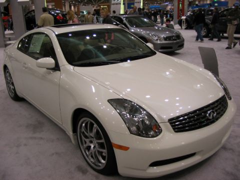 1994 Mazda 626 - White coupe with sunroof and alloy wheels on display at an auto show, with a silver sedan behind it.