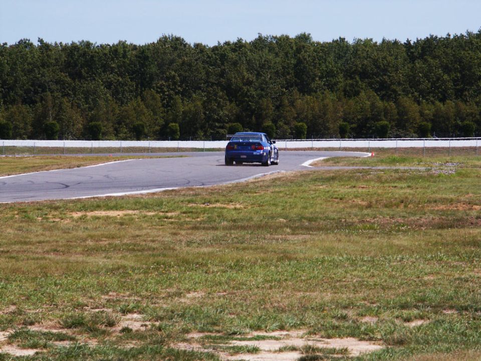 Blue sedan on a race track, rear view