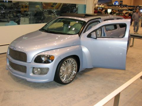1994 Mazda 626 - A light blue custom van with its driver's door open is displayed indoors with large chrome wheels and an aftermarket grille.