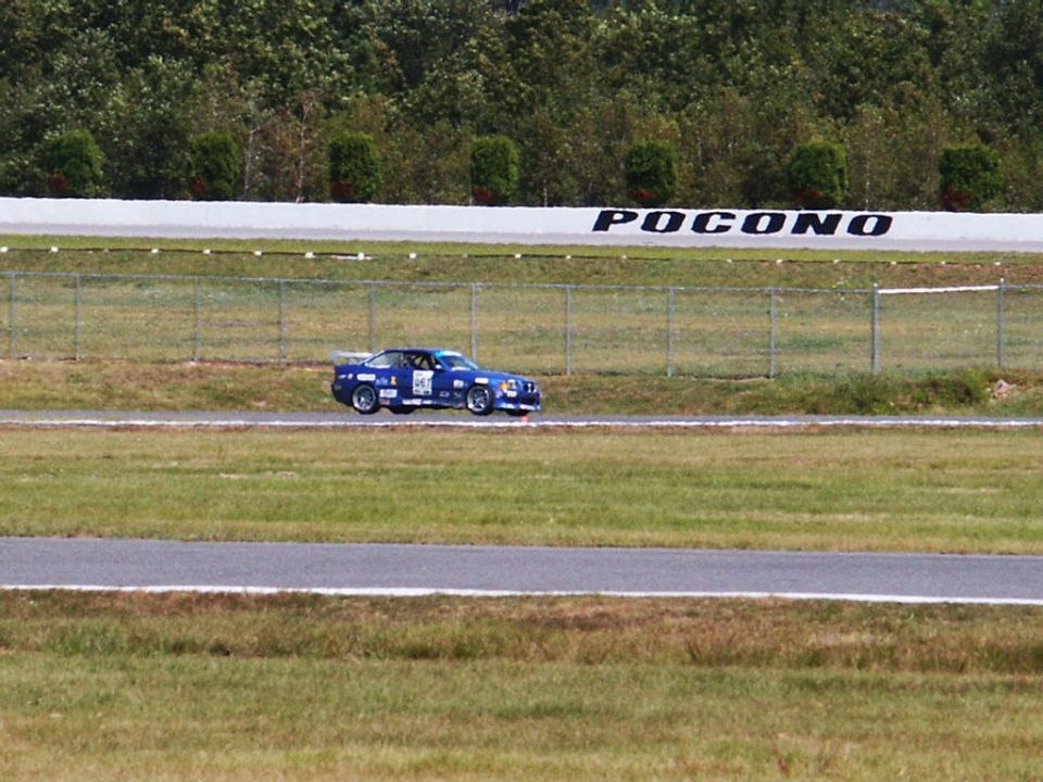 Blue race car on track with 'POCONO' sign