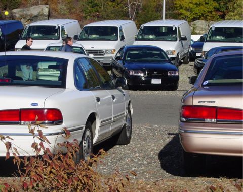 1995 Ford Crown Victoria - A row of vehicles including a white 1995 Ford Crown Victoria is parked in an outdoor lot.