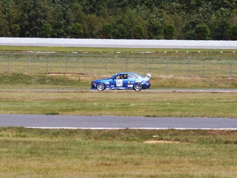 2001 Mercury Grand Marquis - A blue race car is seen on a track, with a spoiler and racing decals visible.