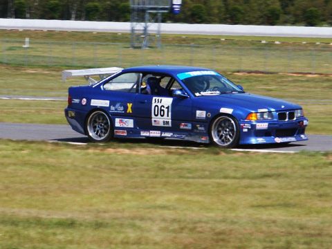 2001 Mercury Grand Marquis - A blue BMW E36 race car is seen on a track, displaying racing decals and the number 061.