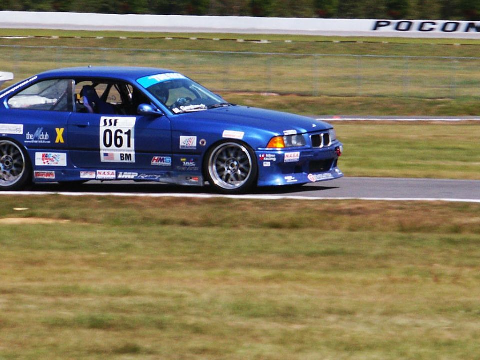 Blue BMW race car with number 061 on the side, on a track